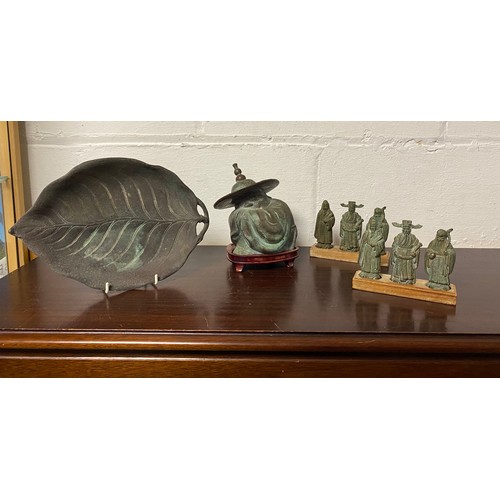 67 - A Chinese bronze of of a man, together with two sets of three bronze immortals and a leaf dish -