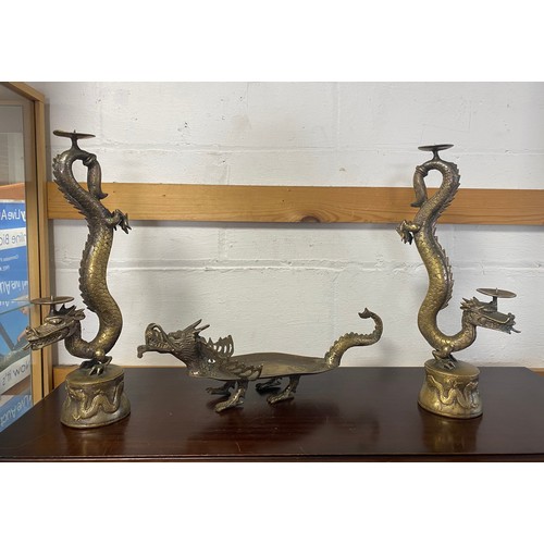 87 - A pair of Chinese brass candlesticks, designed as writhing dragons, together with a similar dragon d... 