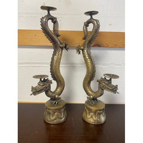 87 - A pair of Chinese brass candlesticks, designed as writhing dragons, together with a similar dragon d... 