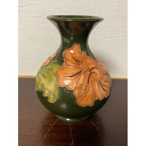 91 - Moorcroft: a hibiscus pattern vase, on a green ground -