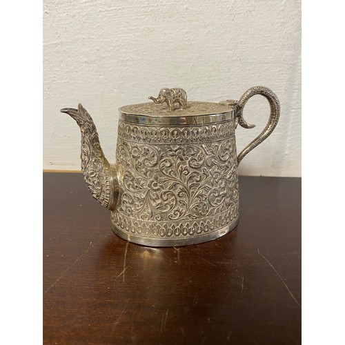 88 - An Indian white metal teapot, with elephant finial to cover, the body decorated with floral and foli... 