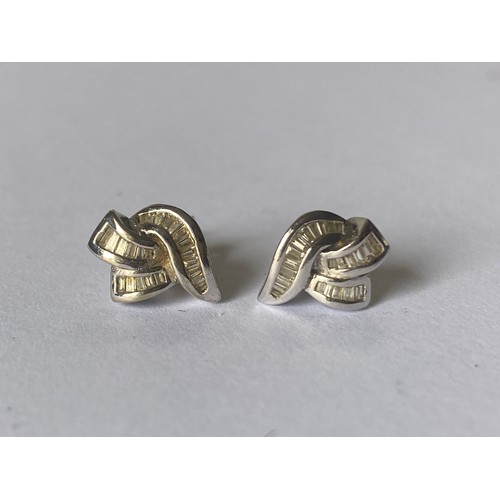 130 - A pair of white gold and diamond earrings, of ribbon design (stamped 750 to backs) -