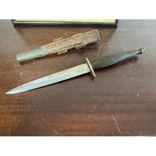 443 - Militaria: a commando knife, with leather sheath and a framed cartoon of a commando -