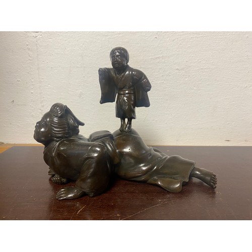 61 - A Japanese bronze, depicting two figures, signed to the underside -