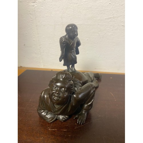 61 - A Japanese bronze, depicting two figures, signed to the underside -