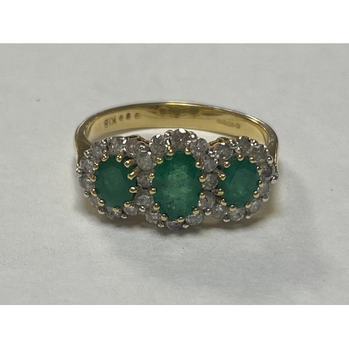 50 - An emerald and diamond ring, of triple oval cluster design, stamped 750 -