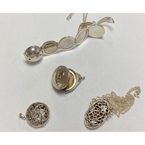 117 - A modern silver fold-out ball locket, together with another swivel locket and two perfume pendants -