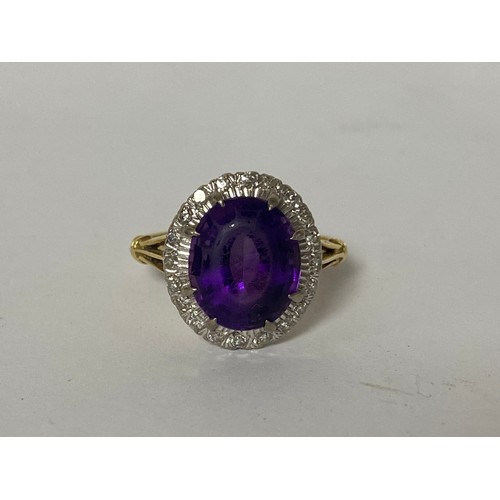 1 - An 18ct gold dress ring, set with an oval purple stone in a border of small diamonds -