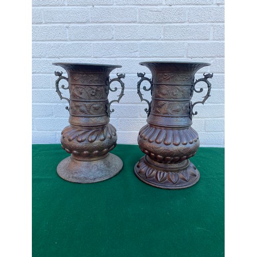 261 - A matched pair of copper urns, each with repousse decoration -