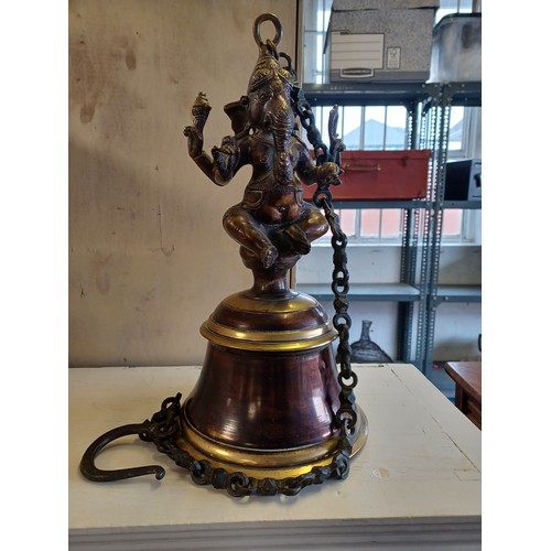 293 - An Indian/Nepalese hanging bell, on chain mount, the bell surmounted by a figure of Ganesh -