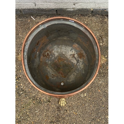 157 - A Victorian brass and copper log bin, with mask ring handles, armorial and fruit decoration and paw ... 