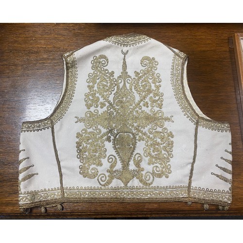 137 - Textiles: an antique child's waistcoat, worked with gold thread on a cream ground -