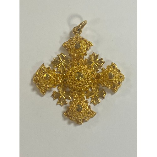 19 - A heavy Middle Eastern yellow metal pendant, of faceted cross design -