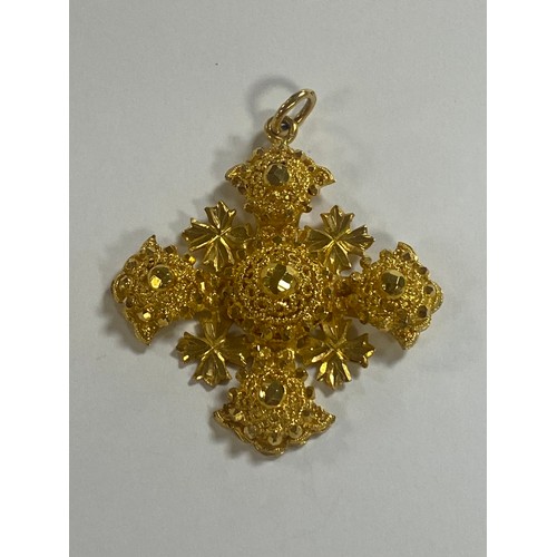 19 - A heavy Middle Eastern yellow metal pendant, of faceted cross design -