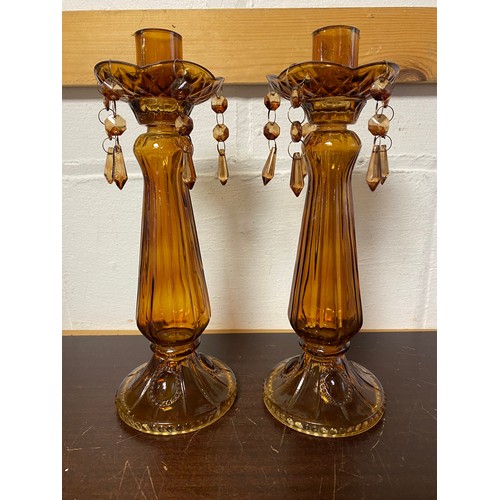 169 - A pair of Edwardian amber glass candlesticks, moulded and with faceted drops -