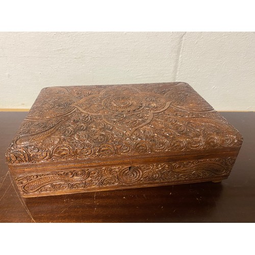 139 - An Indian hardwood box, with elaborately carved decoration, mirror inset to interior, with key -