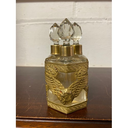 143 - A trio of cut glass scent bottles, in gilt metal stand, decorated with eagle heads