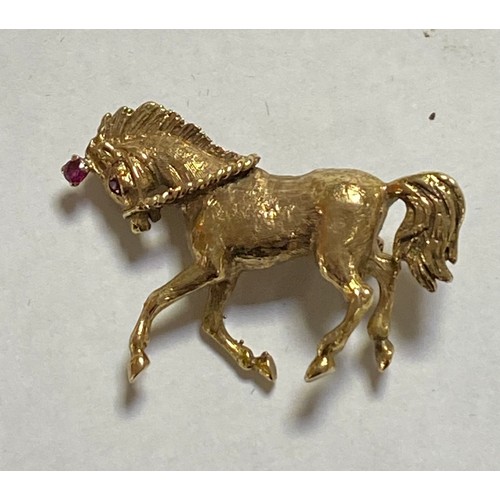 90 - A 9ct gold brooch, designed as a prancing horse, with ruby highlights -