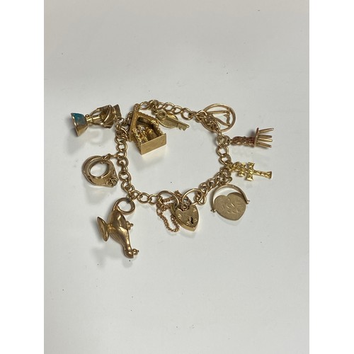 21 - A 9ct gold charm bracelet, with heart padlock clasp and a selection of charms, including Aladdin's l... 