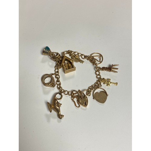 21 - A 9ct gold charm bracelet, with heart padlock clasp and a selection of charms, including Aladdin's l... 