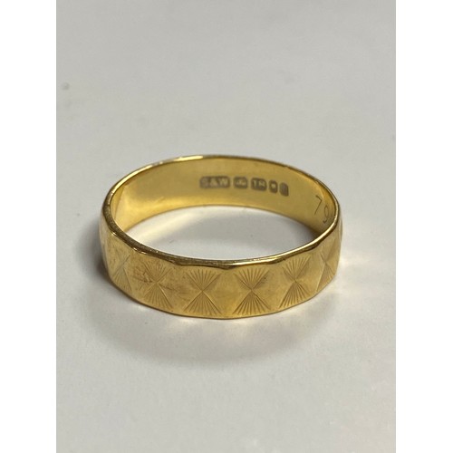 23 - An 18ct gold wedding band, with faceted decoration -