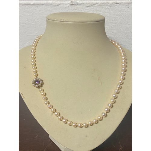 35 - A cultured pearl necklace, the single row of graduated pearls to a 9ct gold clasp set with amethyst ... 