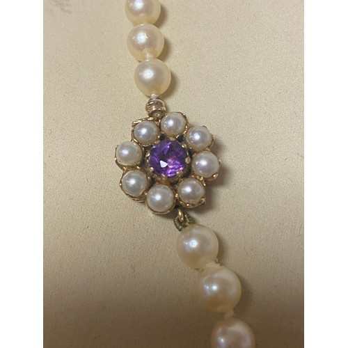 35 - A cultured pearl necklace, the single row of graduated pearls to a 9ct gold clasp set with amethyst ... 