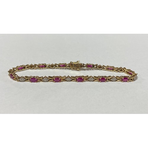 13 - A ruby and diamond line bracelet, composed of oval rubies and diamond clusters, all set in 9ct gold ... 