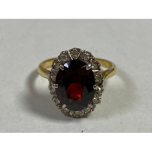 16 - A garnet and diamond cluster ring, of oval design and set in 18ct gold -