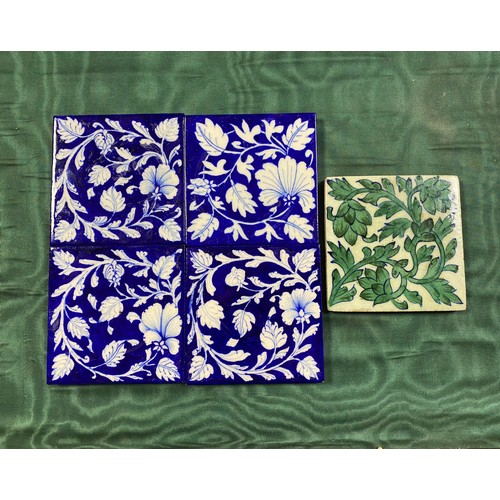 145 - A set of four floral decorated blue and white tiles and another green and white tile with foliate de... 