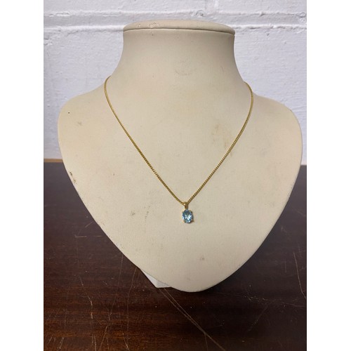 85 - A 9ct gold necklace, suspending an oval blue topaz -