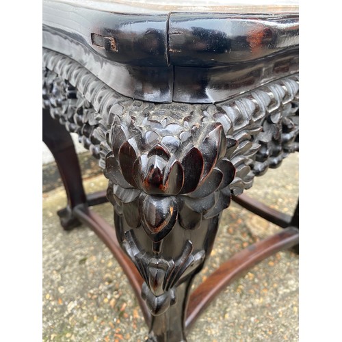 427 - A carved Chinese hardwood table, with elaborately carved frieze, marble inset top and claw and ball ... 