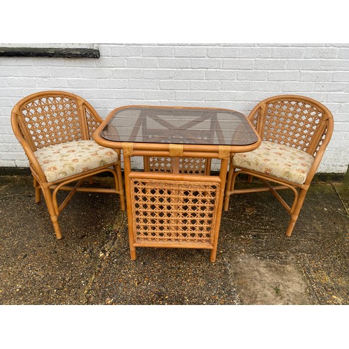 340 - A modern cane conservatory suite, comprising a table with smokey glass top and two armchairs -