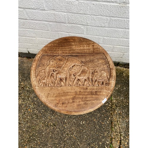 340 - A modern carved hardwood occasional table, the circular top carved with elephants -