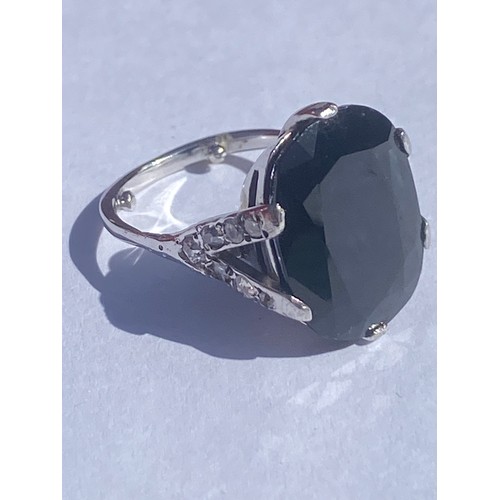 47 - An 18ct white gold dress ring, set with a large dark blue oval sapphire, between diamond set bifurca... 