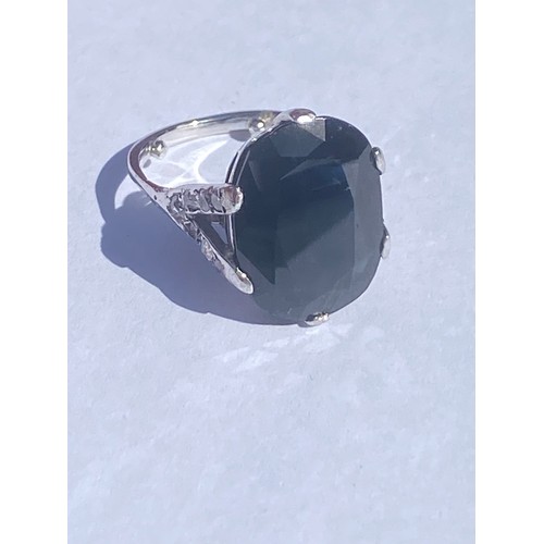 47 - An 18ct white gold dress ring, set with a large dark blue oval sapphire, between diamond set bifurca... 