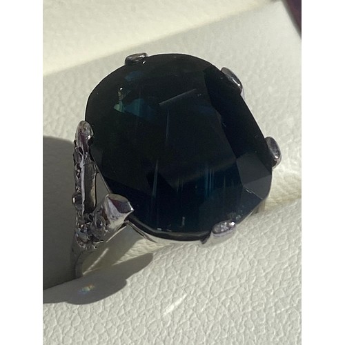 47 - An 18ct white gold dress ring, set with a large dark blue oval sapphire, between diamond set bifurca... 