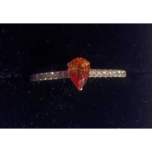 53 - An 18ct gold dress ring, set with a pear cut orange  stone within diamond set shoulders -