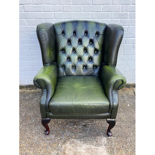 273 - A green button back wingback armchair -