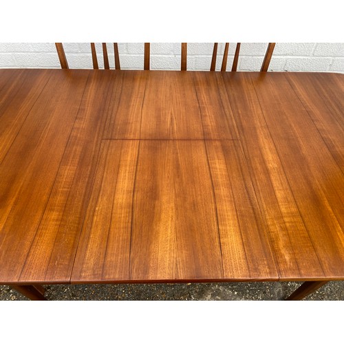 275 - A mid century teak extending dining table, with rounded edge, together with a set of eight associate... 