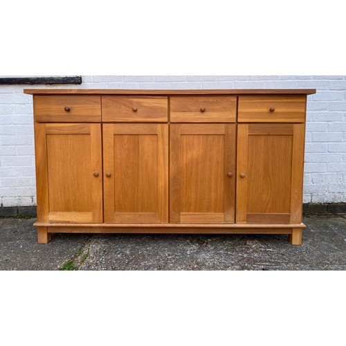 219 - An oak sideboard, with four drawers over cupboard doors and short legs -