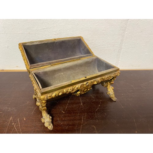 74 - A gilt metal mounted table top casket, of domed shape, with velvet lining and floral scrolling feet ... 