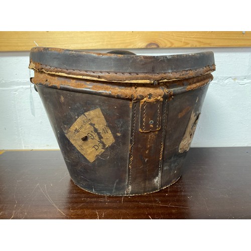 161 - A vintage leather top hat case, with railway labels to exterior and velvet lining -