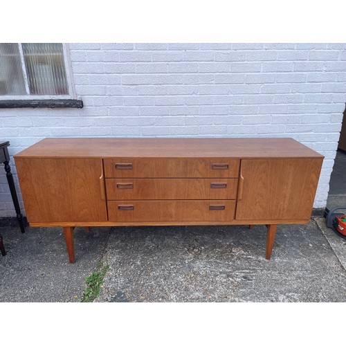 236 - A mid-century teak sideboard, fitted with three drawers flanked by cupboard doors, on tapering legs ... 