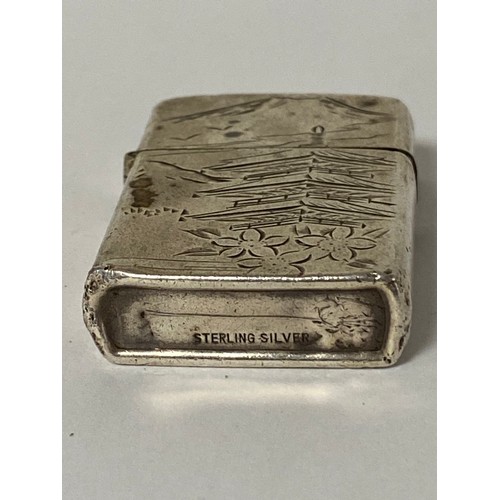 32 - A silver cased lighter, stamped sterling silver, with pagoda and mountain scene -