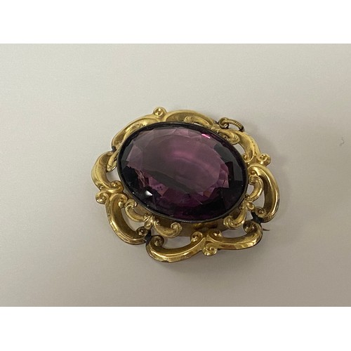 42 - A 19th century brooch, set with amethyst coloured paste in scrolling mount -