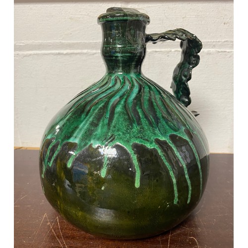 139 - A green glazed pottery flagon, with moulded handle and body and trailing glaze -