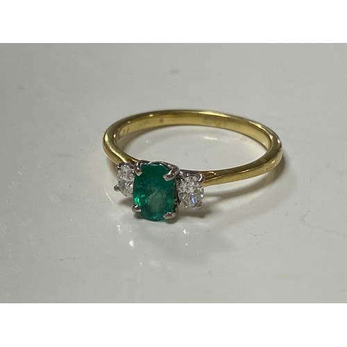 3 - An emerald and diamond three stone ring, the oval emerald between oval diamonds, in precious yellow ... 