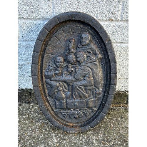 92 - A cast iron oval wall plaque depicting monks -