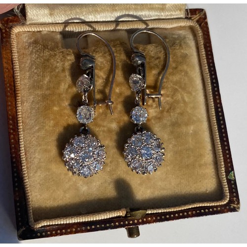 44 - A pair of antique diamond ear pendants, each set with three graduated old cut diamonds above a clust... 